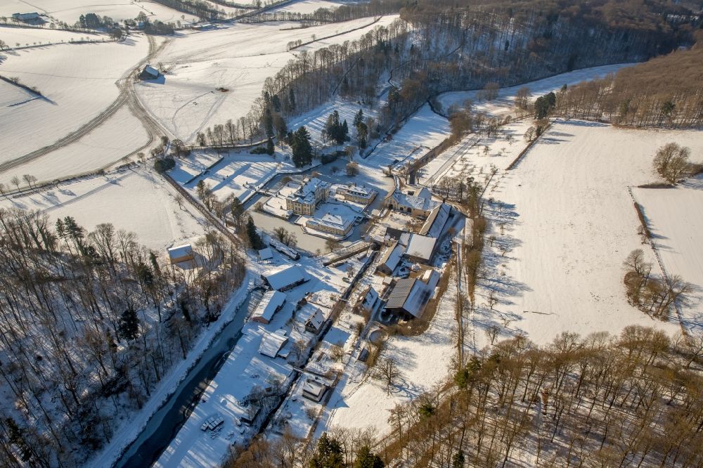 Aerial image Rüthen - Wintry snowy castle Koertlinghausen in the Sauerland region in the state of North Rhine-Westphalia. The baroque water castle is located in the district of Soest and is used today for events and conferences. Originally there was a fortress on site. Today the compound consists of the cottage and main building with 2 wings as well as the courtyard and the adjacent buildings. The castle is located on the river Glenne, surrounded by a ditch