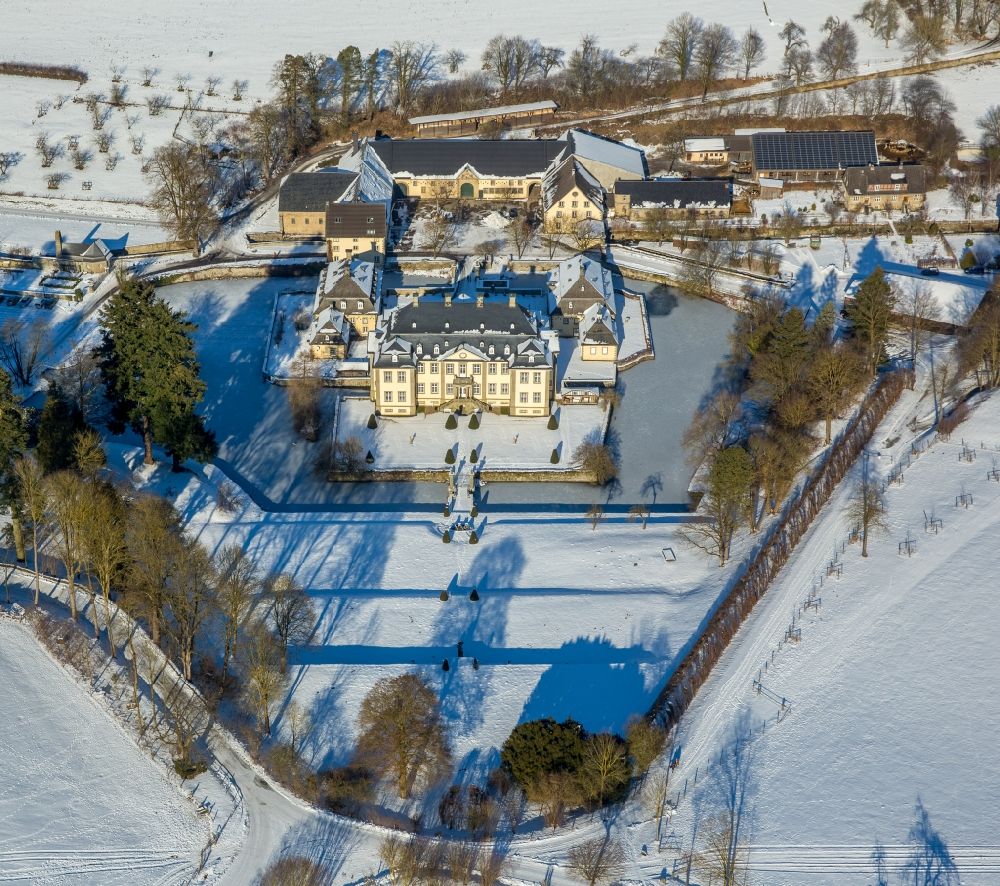 Aerial image Rüthen - Wintry snowy castle Koertlinghausen in the Sauerland region in the state of North Rhine-Westphalia. The baroque water castle is located in the district of Soest and is used today for events and conferences. Originally there was a fortress on site. Today the compound consists of the cottage and main building with 2 wings as well as the courtyard and the adjacent buildings. The castle is located on the river Glenne, surrounded by a ditch