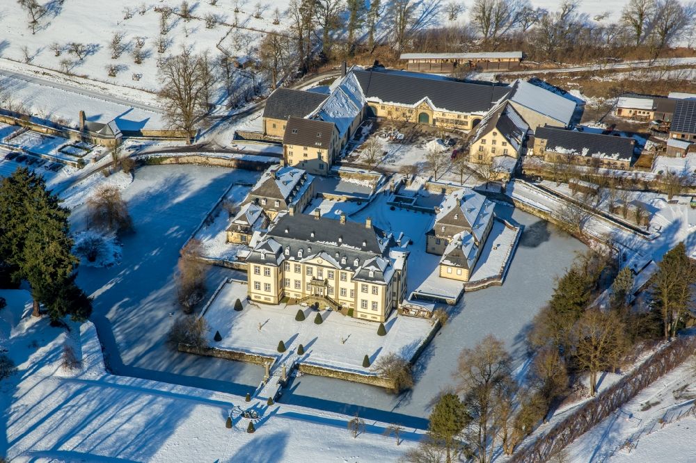 Aerial photograph Rüthen - Wintry snowy castle Koertlinghausen in the Sauerland region in the state of North Rhine-Westphalia. The baroque water castle is located in the district of Soest and is used today for events and conferences. Originally there was a fortress on site. Today the compound consists of the cottage and main building with 2 wings as well as the courtyard and the adjacent buildings. The castle is located on the river Glenne, surrounded by a ditch