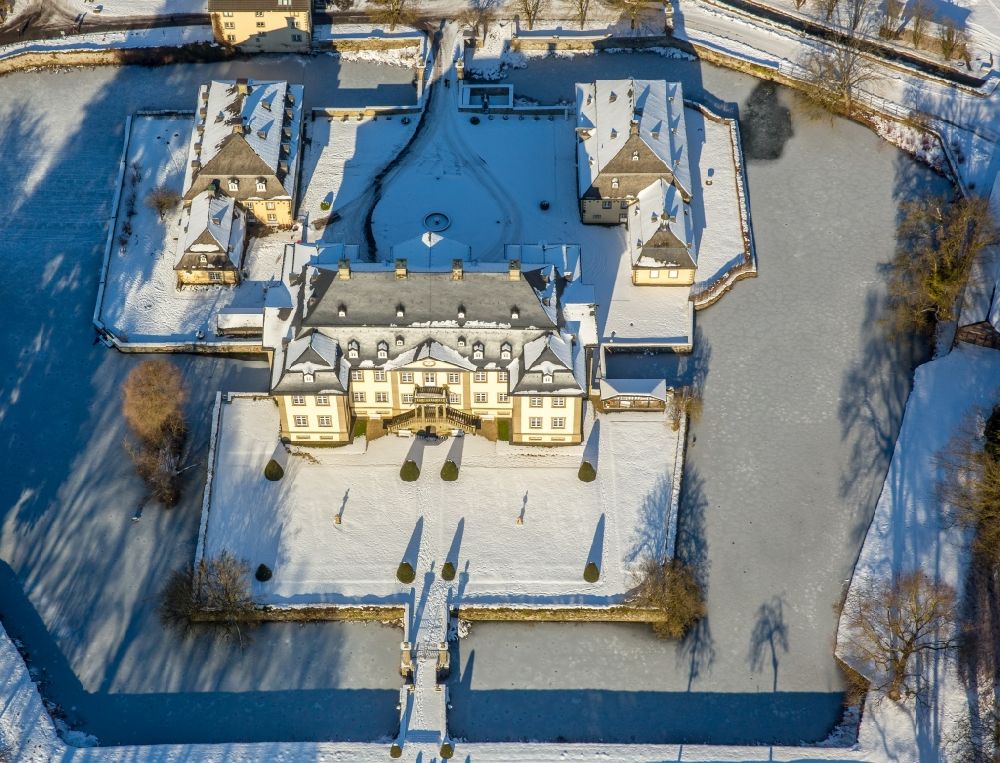 Rüthen from the bird's eye view: Wintry snowy castle Koertlinghausen in the Sauerland region in the state of North Rhine-Westphalia. The baroque water castle is located in the district of Soest and is used today for events and conferences. Originally there was a fortress on site. Today the compound consists of the cottage and main building with 2 wings as well as the courtyard and the adjacent buildings. The castle is located on the river Glenne, surrounded by a ditch