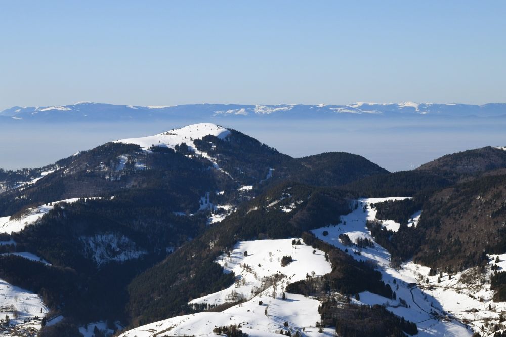 Schönenberg from the bird's eye view: Wintry snowy mountains in the Black Forest at Schoenenberg in the state Baden-Wurttemberg, Germany. Looking over the bold summit of Belchen to the mountain range of the Vosges in France