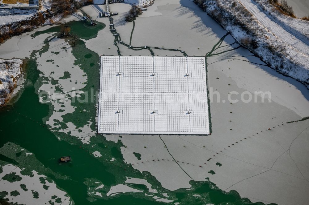 Dettelbach from above - Wintry snowy floating solar power plant and panels of photovoltaic systems on the surface of the water on Dettelbacher Baggersee in Dettelbach in the state Bavaria, Germany