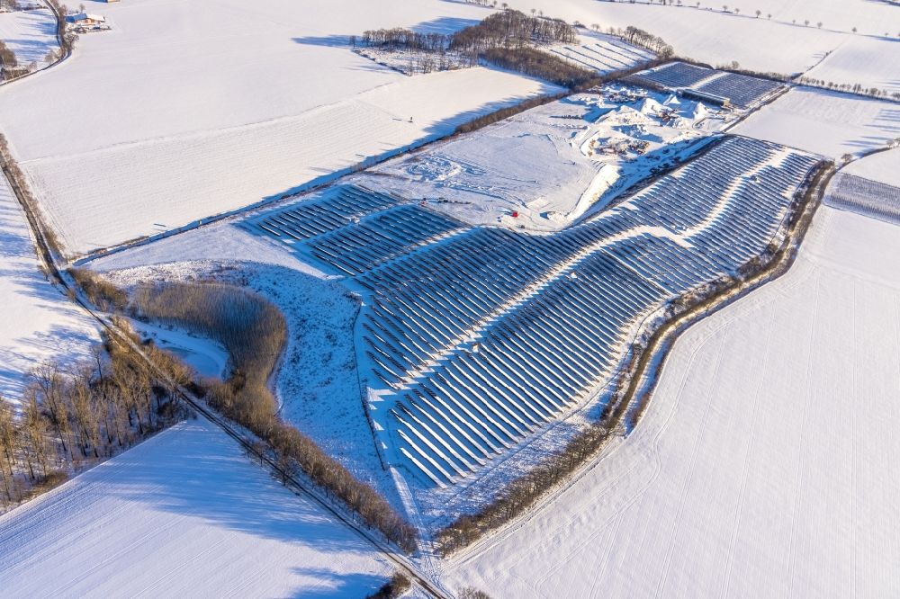 Aerial photograph Büecke - Wintry snowy rows rows of panels of a solar power plant and photovoltaic system Solarpark Moehnesee on a field in Buecke in the state North Rhine-Westphalia, Germany