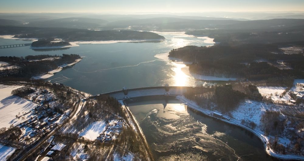 Aerial image Möhnesee - Wintry snowy scenery with the dam - dam and bank areas in the reservoir of the Moehne dam in the district of Guenne in Moehnesee in the federal state North Rhine-Westphalia