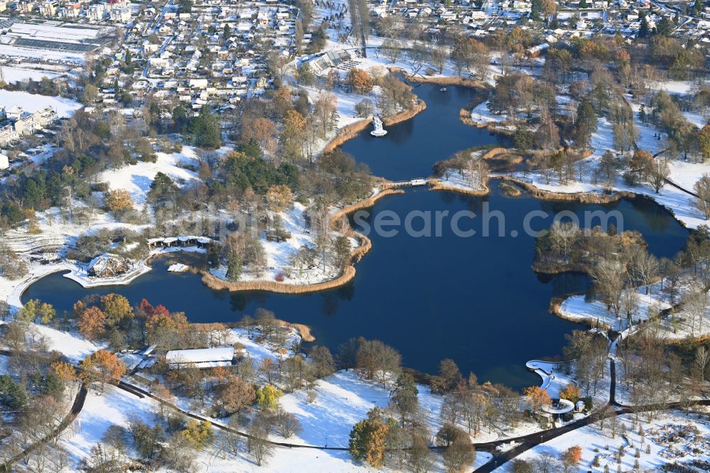 Berlin from the bird's eye view: Wintry snowy riparian areas on the lake area of Hauptsee in the recreation park Britz Garden in Berlin, Germany