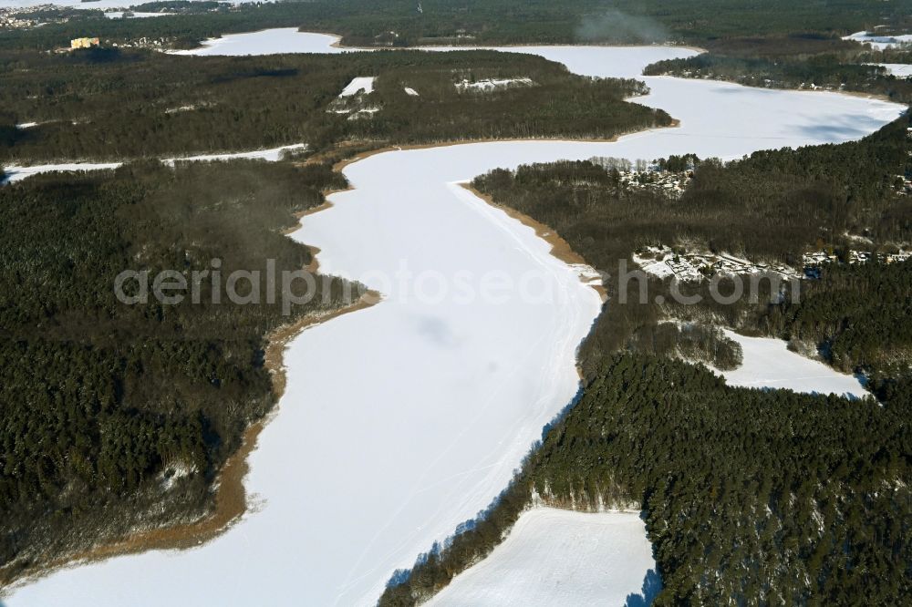 Aerial photograph Templin - Wintry snowy riparian areas on the lake area of Luebbesee in a forest area in the district Ahrensdorf in Templin in the state Brandenburg, Germany