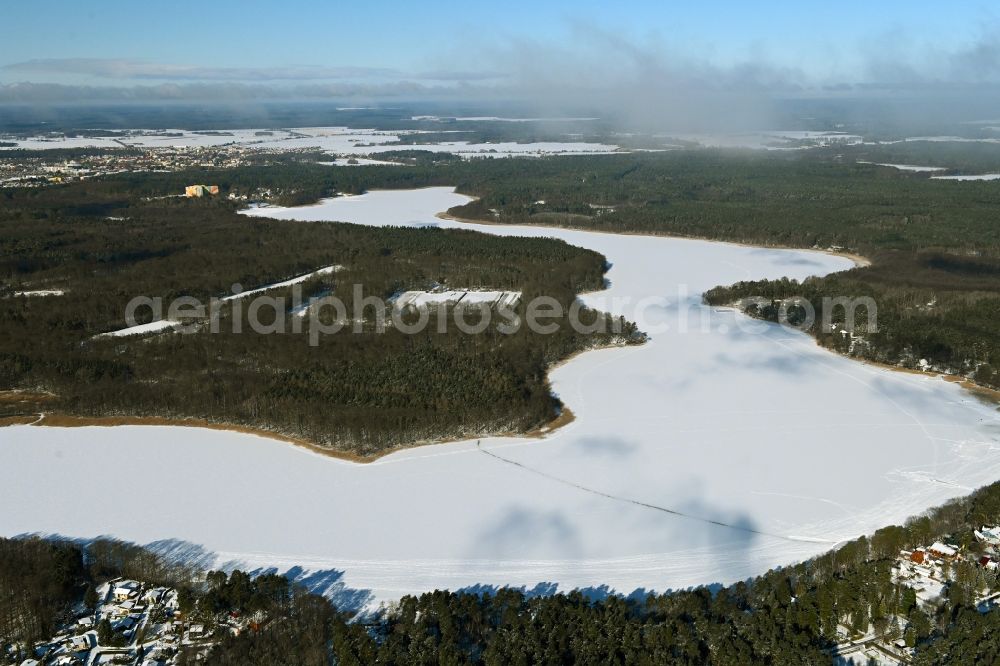 Aerial image Templin - Wintry snowy riparian areas on the lake area of Luebbesee in a forest area in the district Ahrensdorf in Templin in the state Brandenburg, Germany