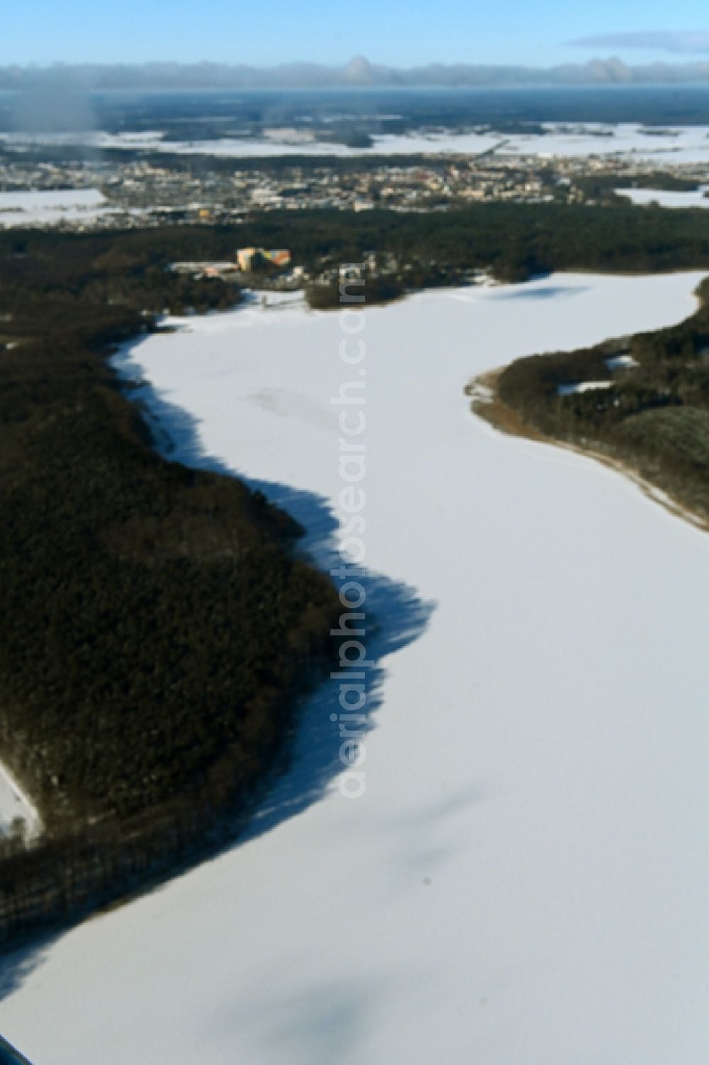 Aerial image Templin - Wintry snowy riparian areas on the lake area of Luebbesee in a forest area in the district Ahrensdorf in Templin in the state Brandenburg, Germany