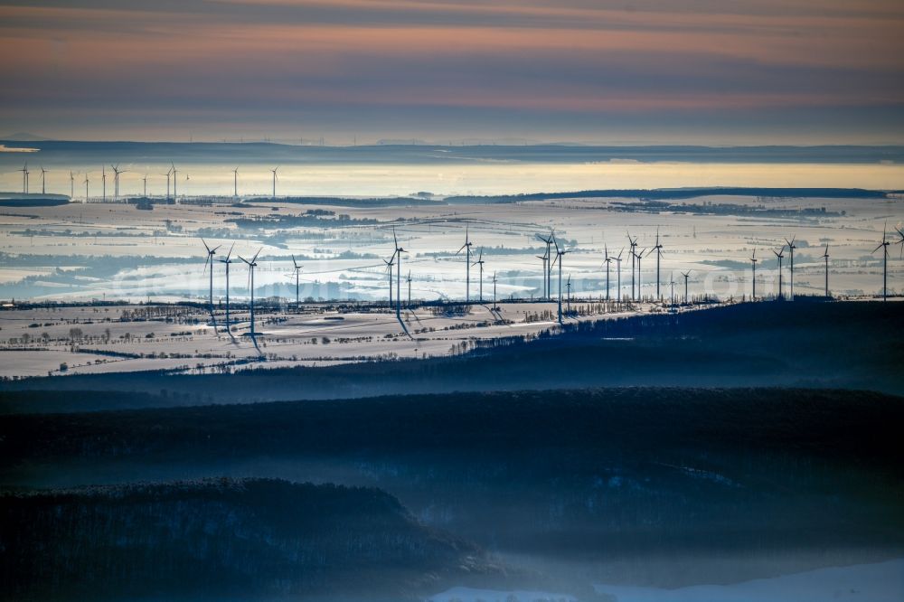 Hachelbich from the bird's eye view: Wintry snowy wind turbine windmills on a field in Hachelbich in the state Thuringia, Germany