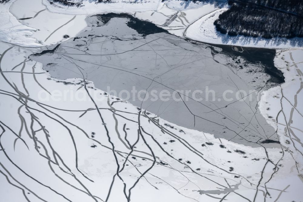 Möhnesee from the bird's eye view: Winter snow-covered reservoirs and shore areas at the frozen reservoir Moehnsee in Moehnesee in the Sauerland in the state of North Rhine-Westphalia, Germany