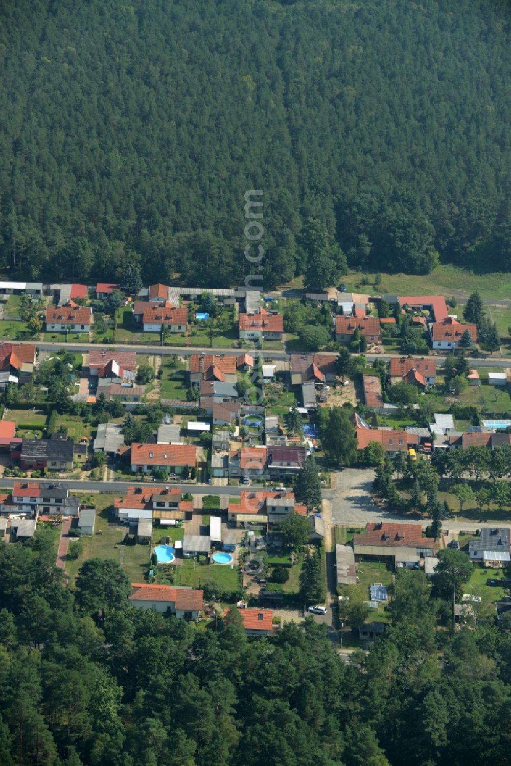 Kummersdorf-Gut from above - Residential area Am Koenigsgraben in a forest in the East of Kummersdorf-Gut in the state of Brandenburg. The residential area with single family and semi-detached houses and gardens is located in a forest along county road L70