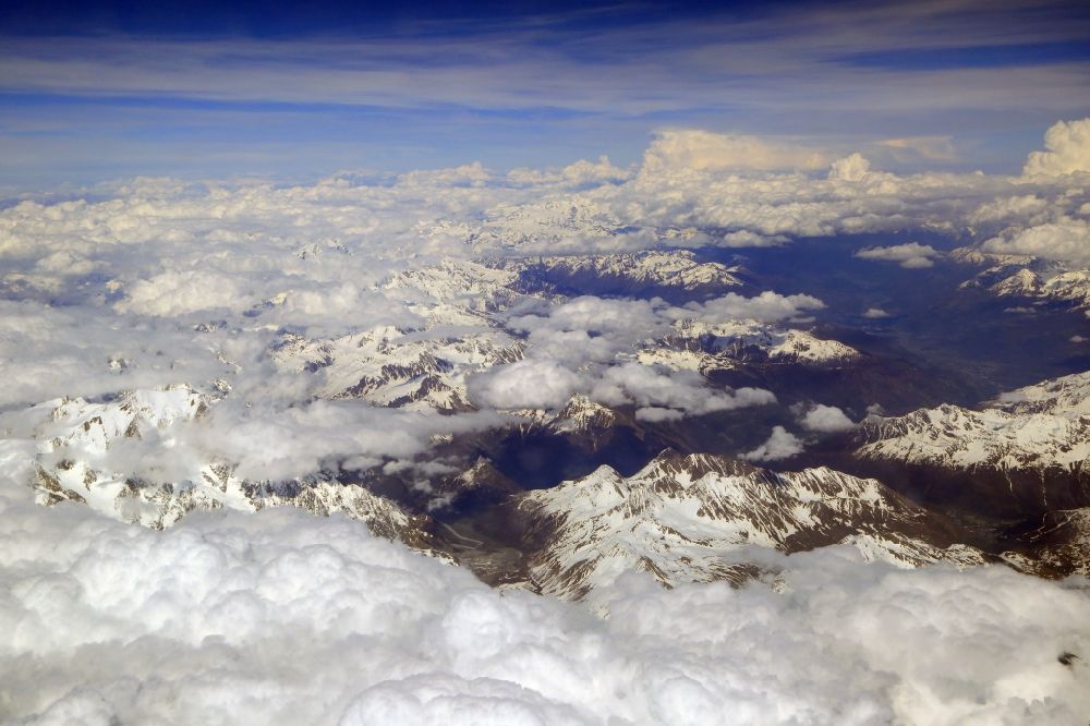 Aerial image Aosta - Clouds over the snow covered summits of the rock and mountain landscape in Valle d'Aosta, Italy