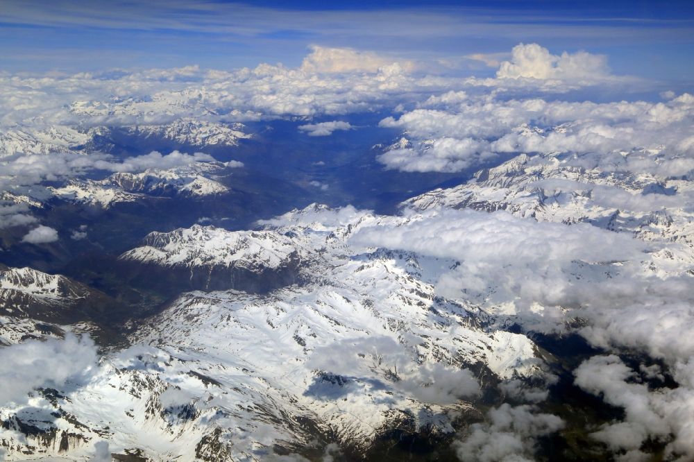 Aerial photograph Aosta - Clouds over the snow covered summits of the rock and mountain landscape in Valle d'Aosta, Italy