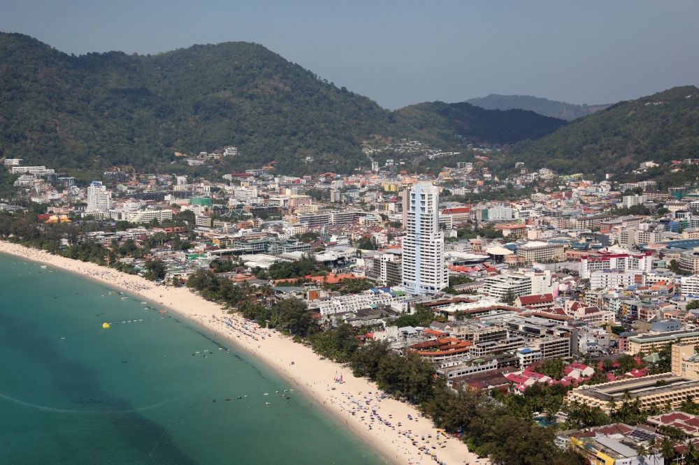 Patong from the bird's eye view: Center and beach of the town Patong on Phuket Island in Thailand. Patong Beach, a beach that runs along the entire western side of the town Patong is the main holiday destination on the island, known for its nightlife and shopping centers. Right of center of the image: the Paton Tower Condominium