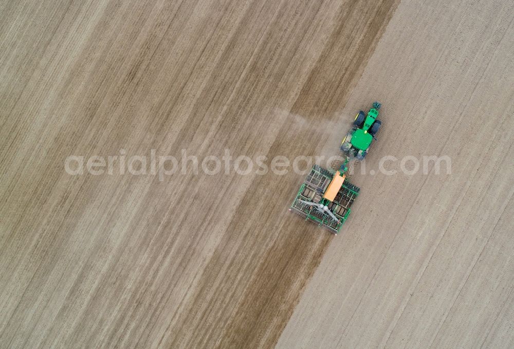 Vertical aerial photograph Seelow - Vertical aerial view from the satellite perspective of the cultivation of a field using a tractor with agricultural machine for sowing in Seelow in the state Brandenburg, Germany