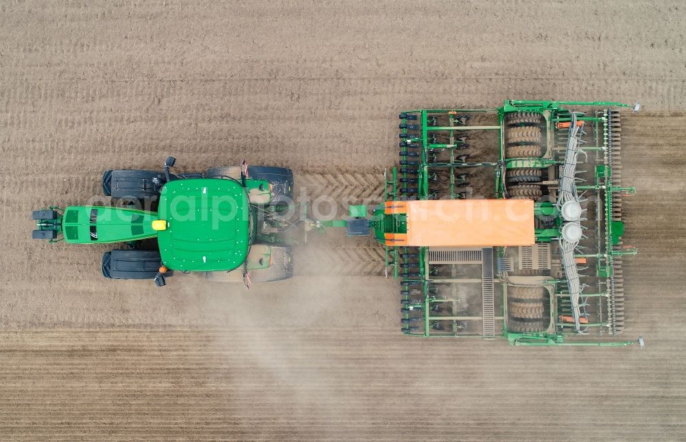 Vertical aerial photograph Seelow - Vertical aerial view from the satellite perspective of the cultivation of a field using a tractor with agricultural machine for sowing in Seelow in the state Brandenburg, Germany